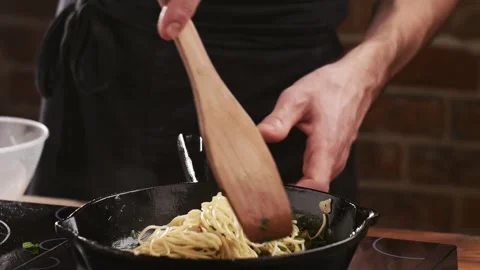 Chef puts spaghetti pasta in a frying pan with fried mushrooms, garlic and Stock-Footage 151205434