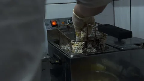 The chef puts squid in a metal mesh deep fat fryer with his gloved hands. Stock Footage 141323905