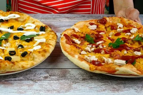 Chef puts on table two homemade pizza with cheese, sausage, chicken meat, oli Stock Photos