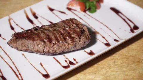 Chef puts tasty stake on the white plate and pours with sauce Stock Footage 73619799