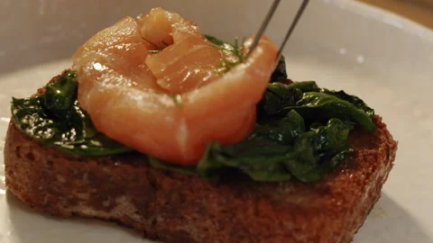 Chef puts thinly red salmon slice on soft juicy spinach toast in slow motion Stock-Footage 150841262