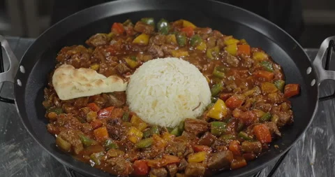 Chef puts Turkish flat bread on a meat with vegetables in an iron plate. Lamb Stock Footage 277849517