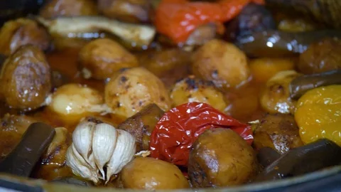 The chef puts vegetables on the dish cooked in a cauldron. Kazan kebab Stock Footage 124731740