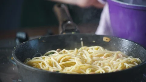 Chef puts vegetables in a pan with spaghetti pasta in a restaurant kitchen. Stock-Footage 124710474