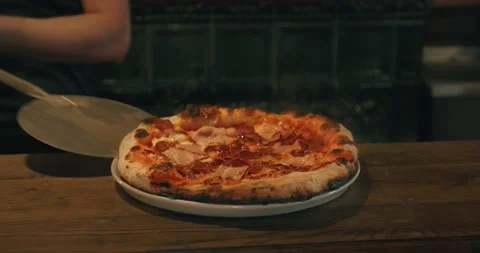 Chef putting baked pizza with meat on plate on wooden table in the kitchen Stock Footage 201467953