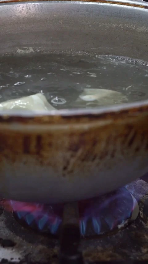 Chef putting fresh dough sheet into boiling water in a cauldron over gas stove b Stock Footage 342627968