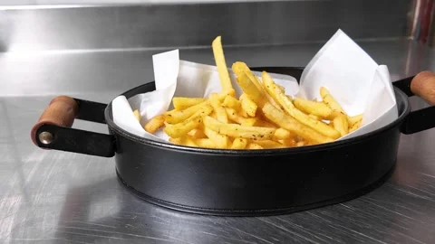 The chef is putting fried potatoes in a black pan with a wooden handle. Stock Footage 278348317