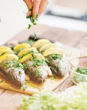 Chef putting greenery on fish with lemons. Stock Photos