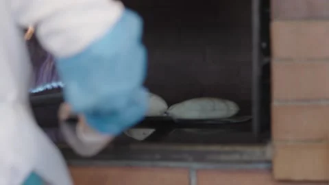 A chef putting out a puffed pastry from a brick oven using a flat pizza Stock Footage 194435123