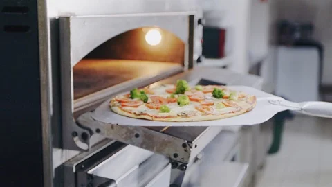 Chef putting pizza into an oven. Baking pepperoni pizza Бесплатное стоковое видео 104720090