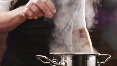 Chef putting raw pasta into boiling water. White smoke in slow motion rising Stock Footage 151119543