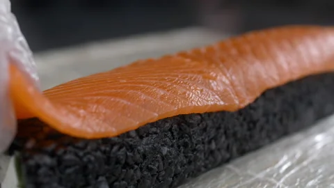 Chef raw salmon to the black rice roll and makes sushi Stock Footage 143779392