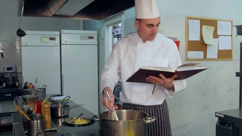 Chef reading cook book and making some dish 스톡 동영상 72321251