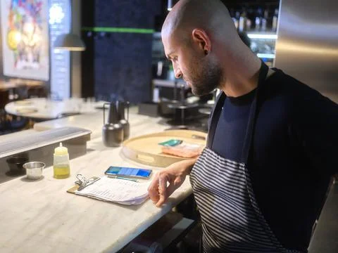 Chef reading the list of tasks to prepare the menu in a restaurant Stock Photos