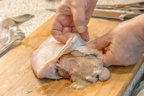 Chef removes the skin from a fresh flounder fish for further cooking Foto stock
