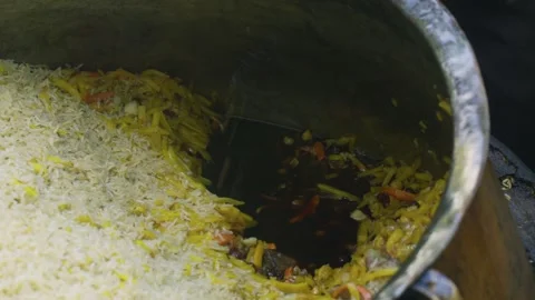 Chef removing bones from Uzbek plov in huge cauldron, close-up Stock Footage 332893931