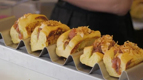 Chef removing a large, juicy hot dog from the grill and placing it in bun to Stock Footage 261058827