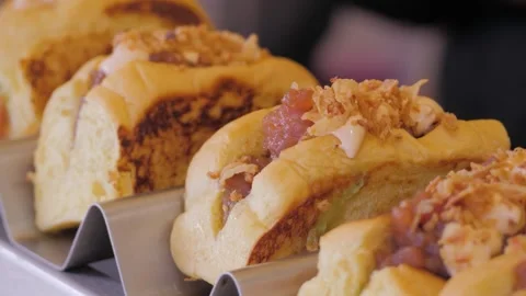 Chef removing a large, juicy hot dog from the grill and placing it in bun to Stock Footage 261058853