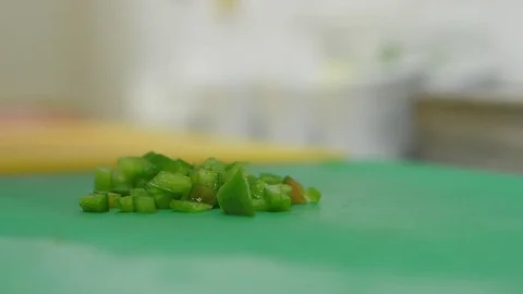Chef removing pieces of green pepper from the kitchen table slow motion Stock Footage 76890748