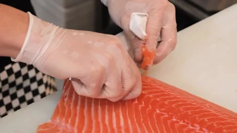 Chef removing pin bones from fresh salmon fillet with tweezers in kitchen Stock Footage 333489242