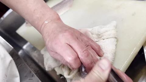Chef removing pin bones from a fresh Japanese sea bass fillet (suzuki) Stockbeeldmateriaal 339743075
