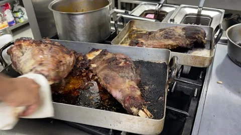Chef removing roasted lamb legs from oven tray 스톡 동영상 344100001