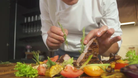 Chef At Restaurant Kitchen Adds Final Ingredients In Grilled Meat Steak Platter. Vidéo 142819733