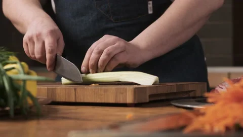 Chef in restaurant kitchen cuts celery with sharp, shiny knife. man prepares Stock Footage 150666273