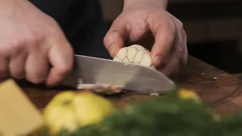Chef in restaurant kitchen cuts garlic with sharp, shiny knife. man prepares Stock Footage 150627100