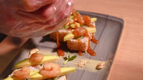 Chef in restaurant kitchen decorating delicious rolls with sesame sauce bottle Stock Footage 269546300