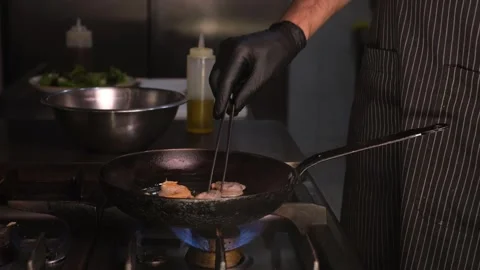 Chef in restaurant kitchen frying shrimp on hot skillet close-up of hands side v Stock Footage 334126581
