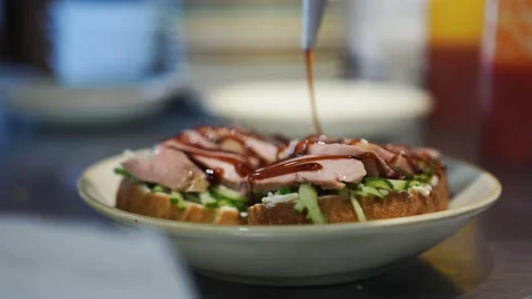 The chef in the restaurant kitchen pours delicious sauce, bruschetta on a plate Stock Footage 141790655