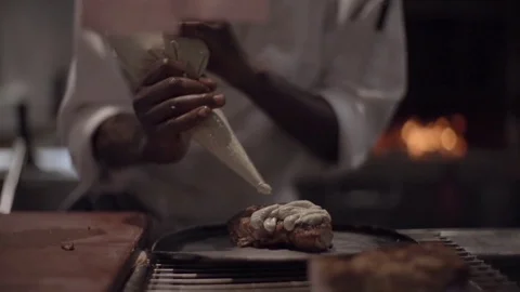 Chef in restaurant kitchen putting cream on grilled steak Stock Footage 72981266