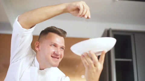 Chef At Restaurant Kitchen Serves Dish On A Plate Adding Final Ingredients. 動画素材 142817905