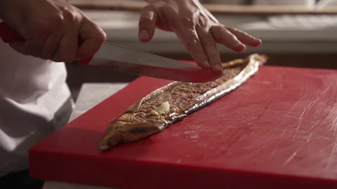 Chef in a restaurant kitchen slicing a traditional Turkish pide Video stock 336676238