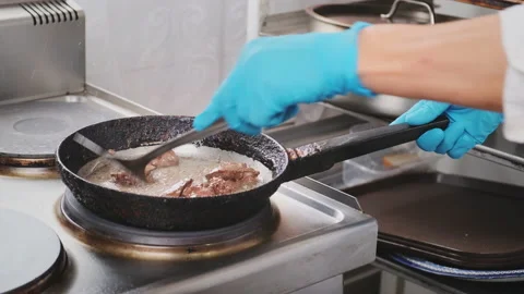 Chef in restaurant kitchen stirs and turns meat Stock Footage 218404181
