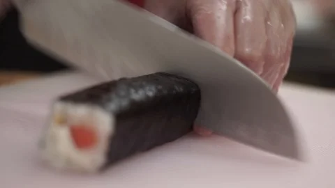 Chef in restaurant preparing and Cutting sushi rolls healthy food Stock Footage 106670210