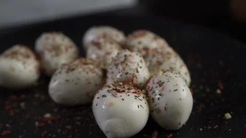 The chef in the restaurant sprinkles the mozzarella on a black plate with herbs. Stock Footage 143418347