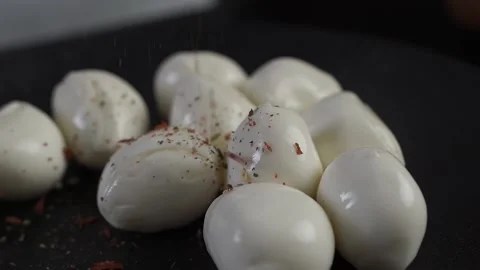 The chef in the restaurant sprinkles the mozzarella on a black plate with herbs. Stock Footage 143611864