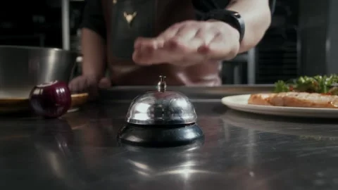 Chef rings the tabletop bell when a dish is ready in a restaurant kitchen. Stock Footage 314577226