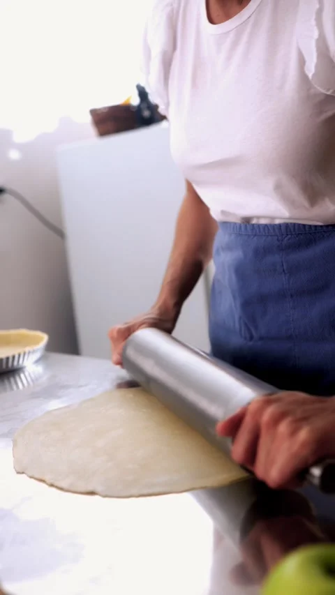 Chef rolling dough with rolling pin in kitchen - Homemade apple pie preparation Stock Footage 329456485