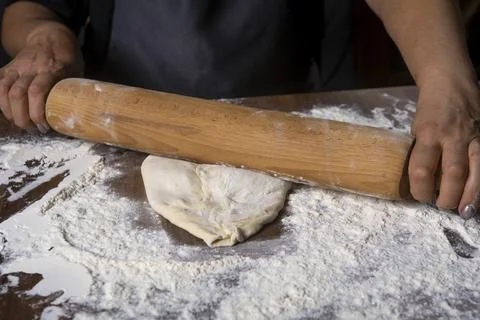 Chef is rolling the dough with the rolling pin on the on the table. Hands clo Stock Photos