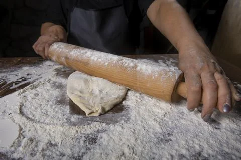 Chef is rolling the dough with the rolling pin on the on the table. Hands clo Stock Photos