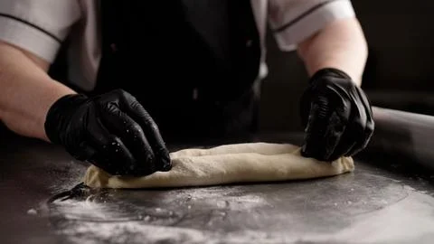 Chef rolling dough with rolling pin on stainless steel table Stock Photos