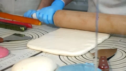 A chef rolling out soft caramel with a rolling pin on a table in a pastry shop. Stock Footage 330522295