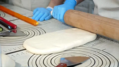 A chef rolling out soft caramel with a rolling pin on a table in a pastry shop. Stock Footage 331147281