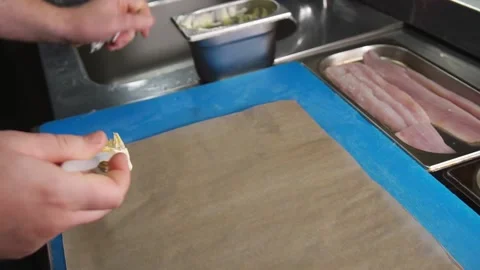Chef rolling up white cod fish for baking in a Parchment Pape renvelope Stock Footage 205152586