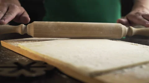 Chef rolls out the dough with a rolling pin on the kitchen table Stock Footage 143779467