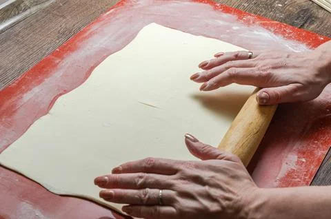 The chef rolls out the dough with a rolling pin Stock Photos