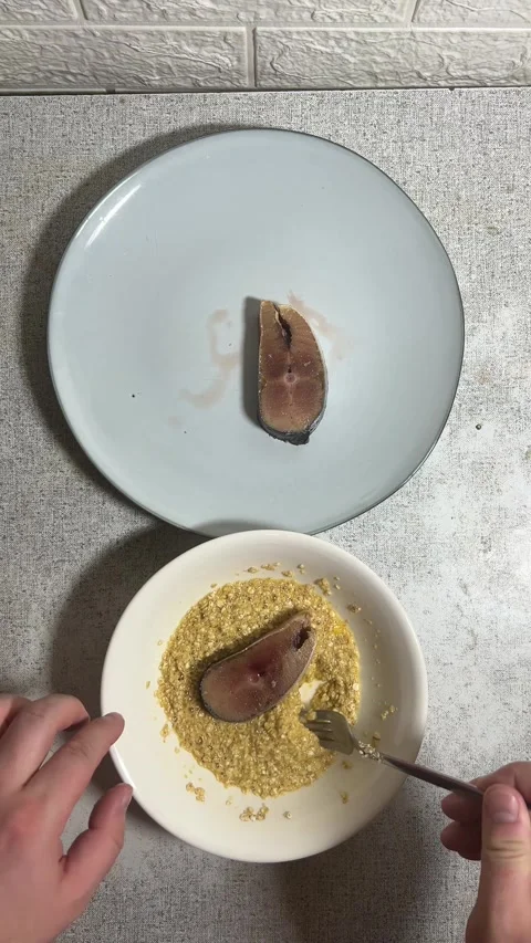 Chef rolls piece of fish in plate with batter, egg, oatmeal, flour before frying Video stock 288919372